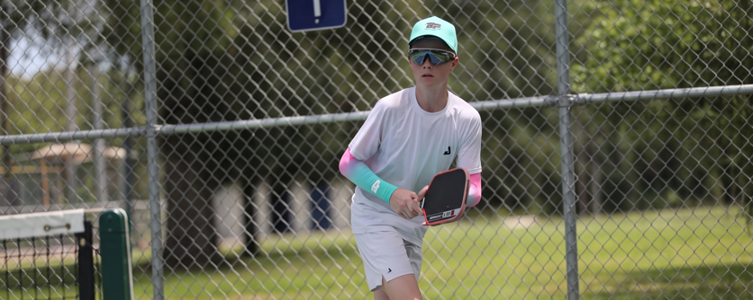 Austin Romaguera lunging for a low forehand at a professional pickleball tournament